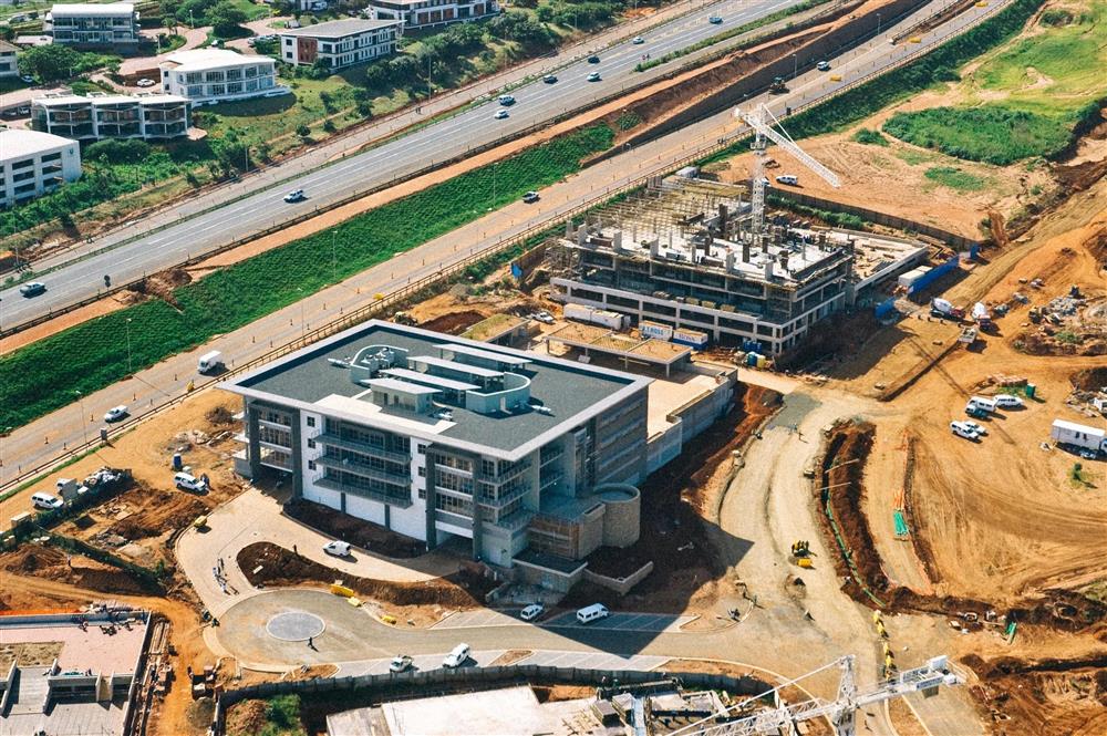 Aerial view of an office building under construction beside a highway and graded land
